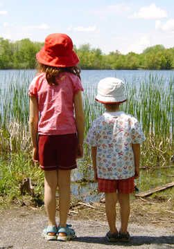 Two girls standing and looking at a lake